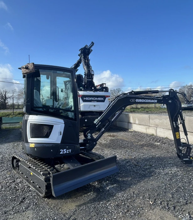 Chantier extérieur avec mini-pelle compacte Hidromek 25ZT équipée de chenilles en caoutchouc et cabine vitrée