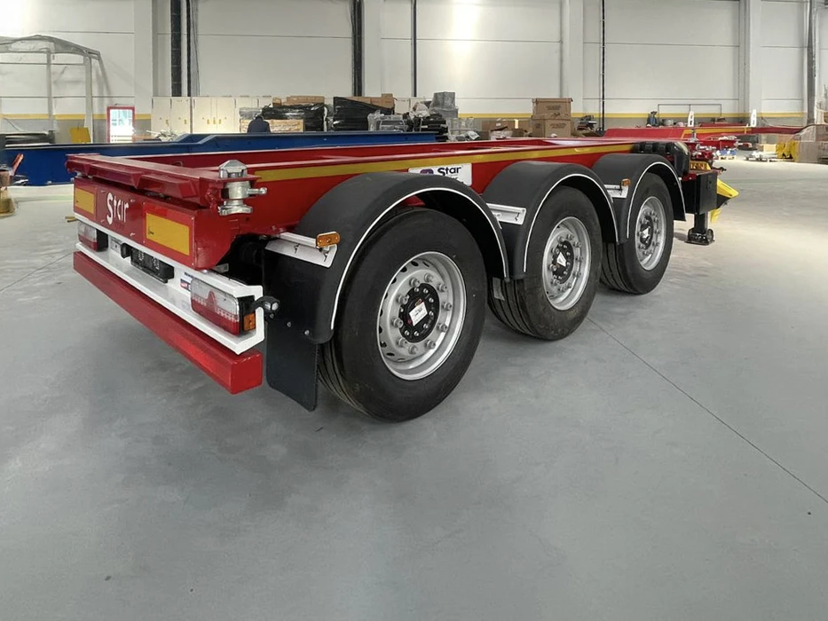 Scène extérieure d'un concessionnaire d'équipements de construction avec plusieurs engins de chantier stationnés devant un bâtiment métallique marqué "OZ TRUCK TRAILER"