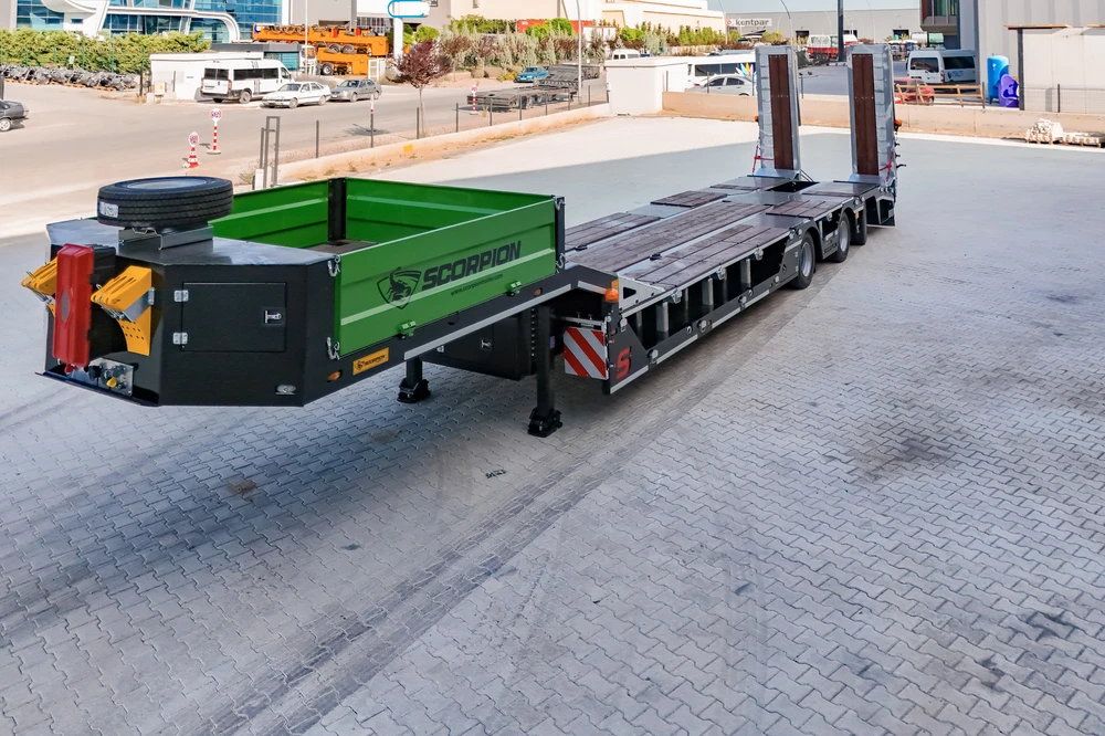 Scène extérieure avec pelleteuse sur chenilles Hidromek chargée sur semi-remorque rouge à trois essieux