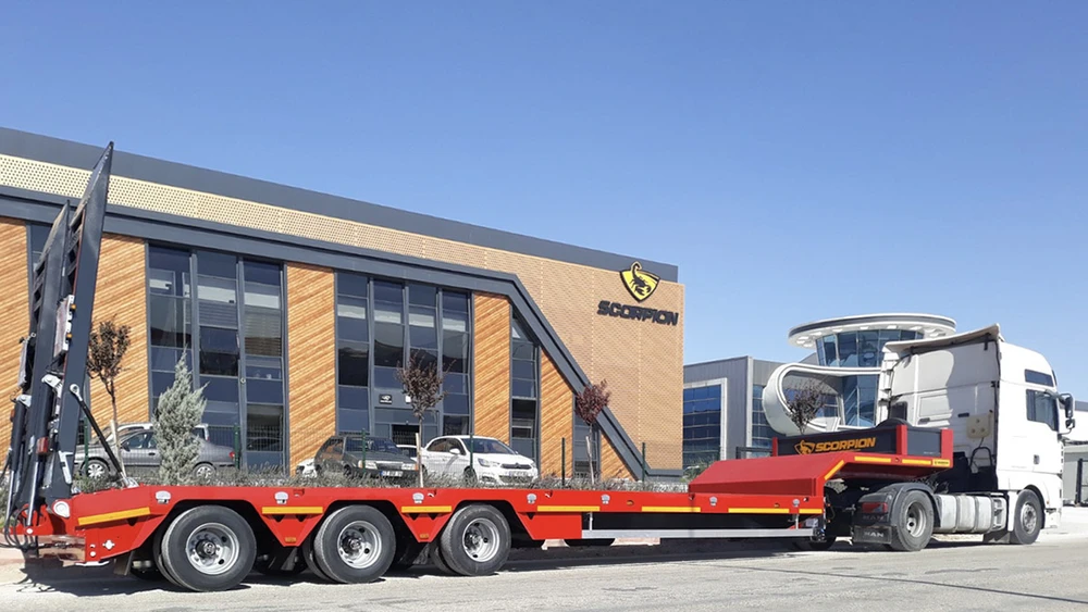 Scène extérieure d'un chantier avec chargeuse compacte Kramer stationnée devant hangar métallique ouvert