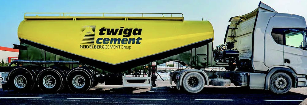 Scène extérieure d'un chantier avec chargeuse compacte Kramer stationnée devant hangar métallique ouvert