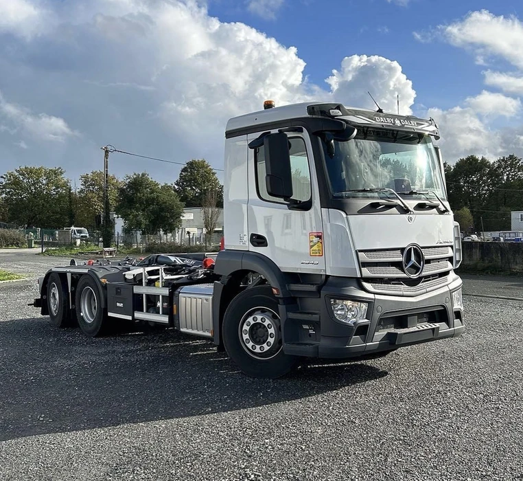 Scène extérieure d'un chantier avec chargeuse compacte Kramer stationnée devant hangar métallique ouvert