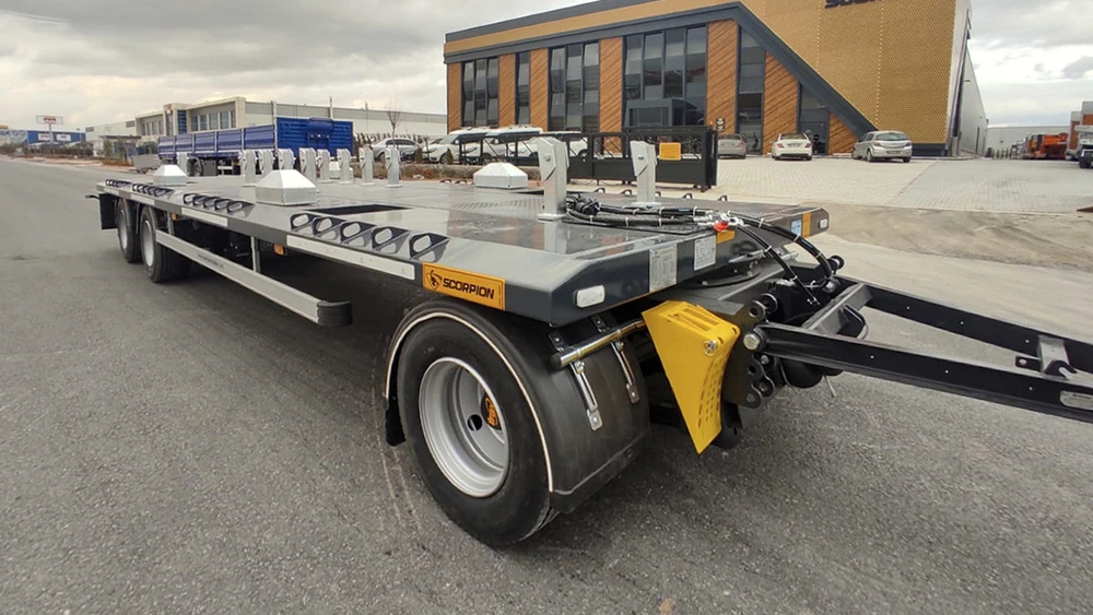 Camion semi-remorque avec plateau surbaissé rouge stationné devant bâtiment industriel moderne
