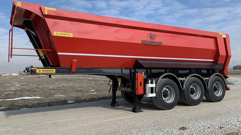 Camion semi-remorque avec plateau surbaissé rouge stationné devant bâtiment industriel moderne