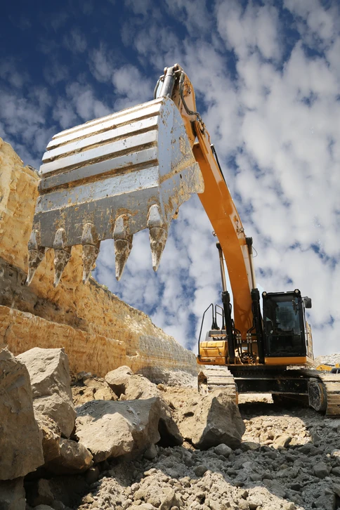 Scène extérieure sur pelouse verte avec personne portant gants noirs effectuant maintenance sur tondeuse autoportée